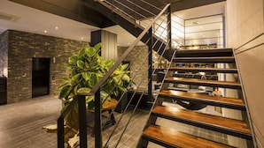 A modern interior with a wooden staircase, a brick wall, and a potted plant. - Trang BLUE (Seoul)