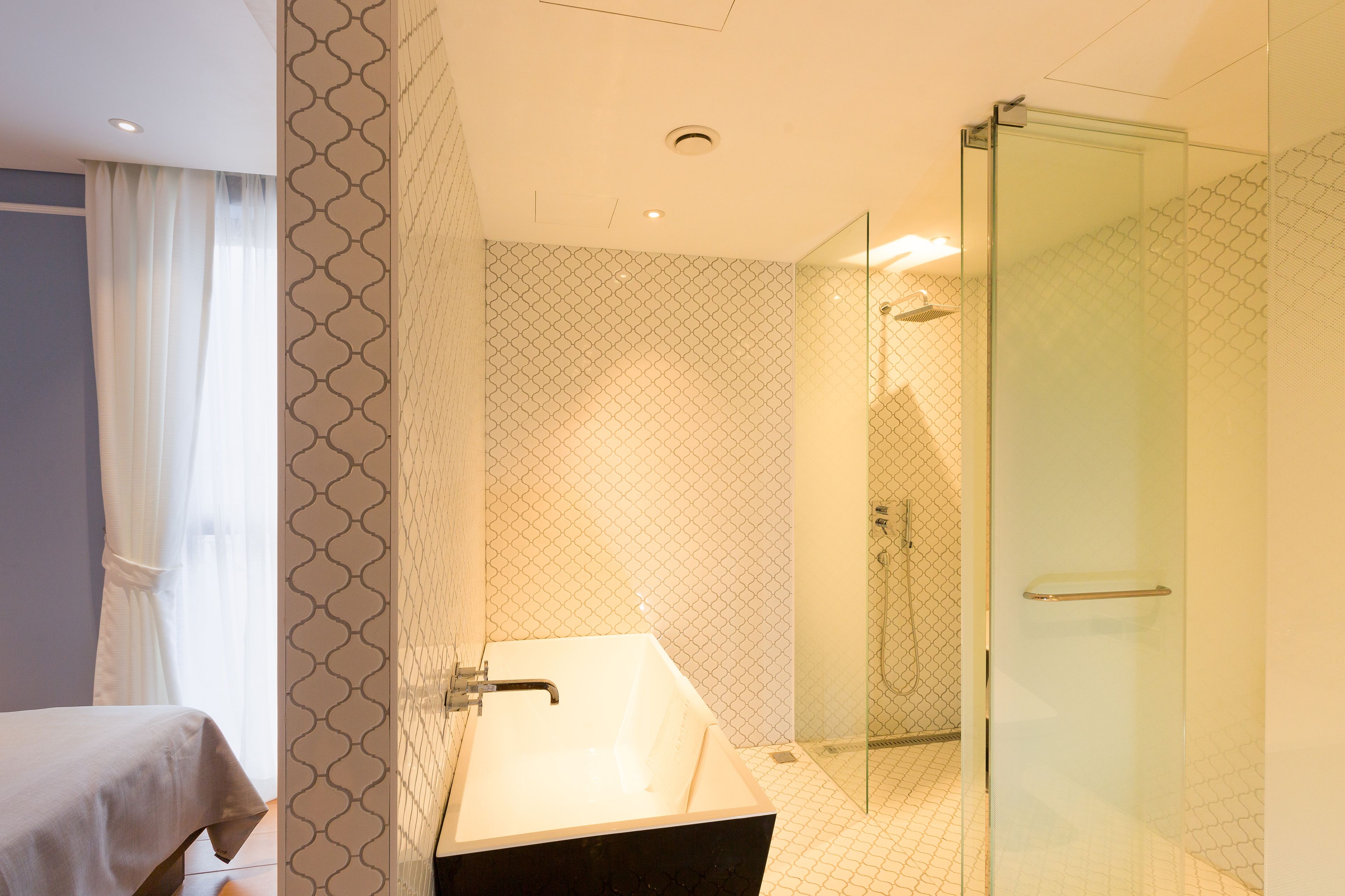Un baño moderno con ducha envuelta en vidrio, una bañera independiente y paredes con diseño.
