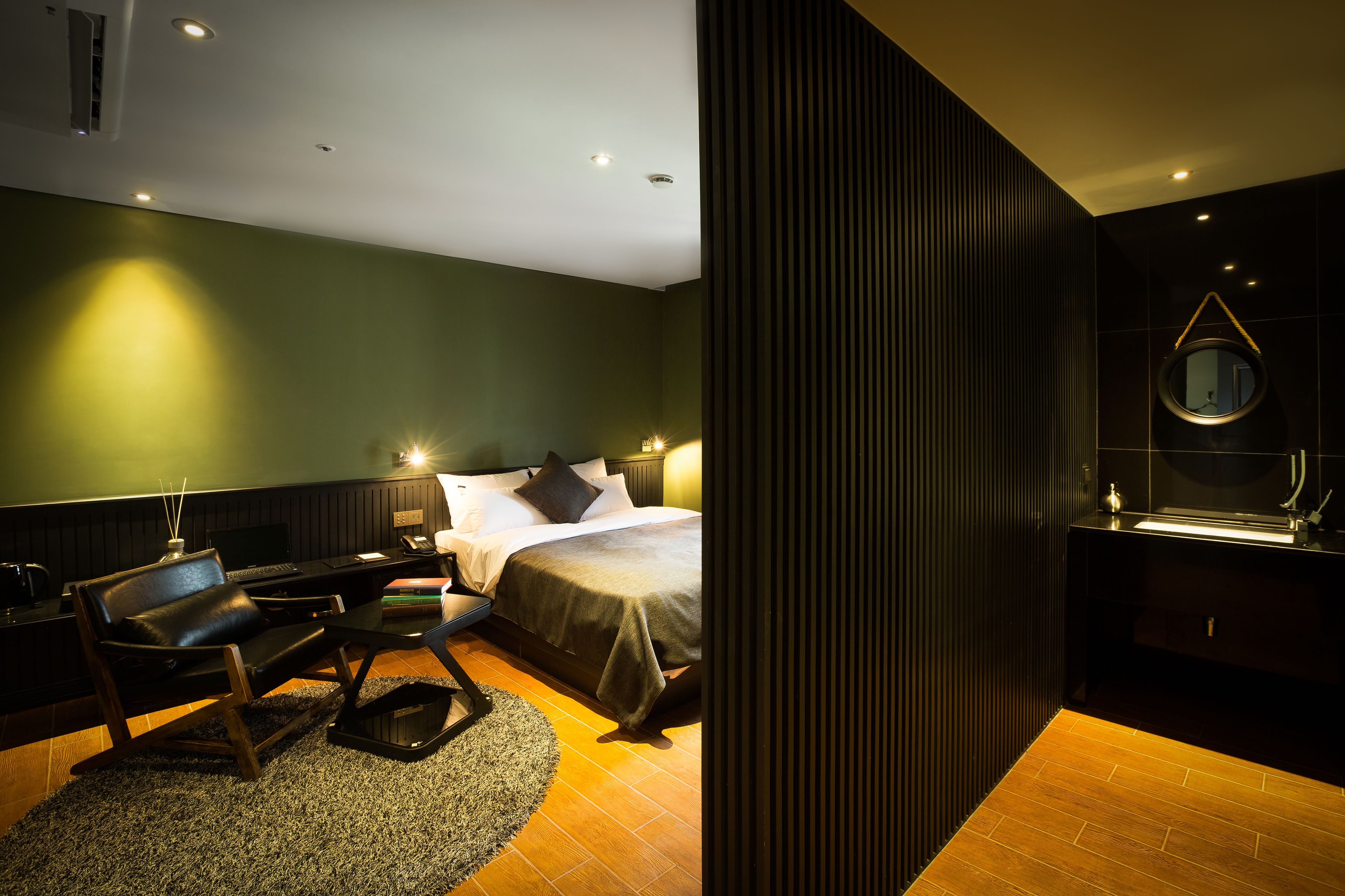 Une chambre d’hôtel moderne équipée d’un lit, d’un bureau, d’une chaise et d’une salle de bain avec un miroir.