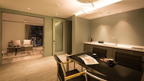 A modern hotel room with a dining area, a sofa, and a view of the city at night. - Trang BLUE (Seoul)