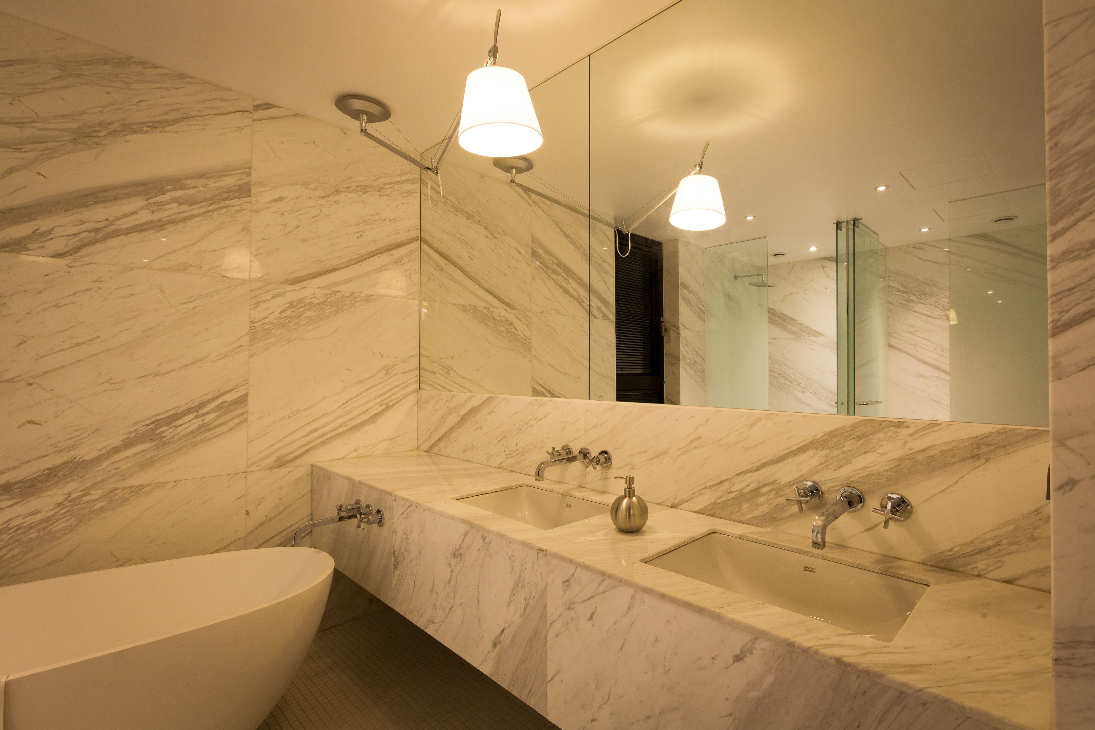 A modern bathroom with a large marble sink, a bathtub, and a large mirror.
