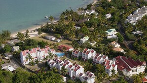 An aerial view of a coastal residential area with houses, a beach, and dense greenery. - Ocean Villas Apart Hotel (Grand-Baie)