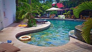 A swimming pool with a wooden deck, lounge chairs, and umbrellas. - Ocean Villas Apart Hotel (Grand-Baie)