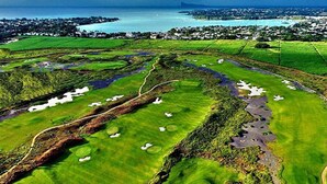 A golf course with multiple holes, water hazards, and a view of a coastal town in the background. - Ocean Villas Apart Hotel (Grand-Baie)