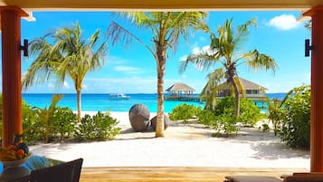 Vista de una playa con muelle de madera, palmeras y un mar azul cristalino.