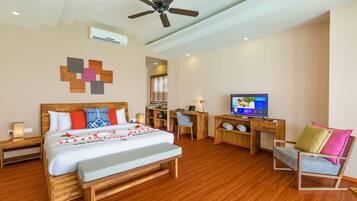 A modern hotel room with a wooden bed, a desk with a computer, a TV, and a ceiling fan.