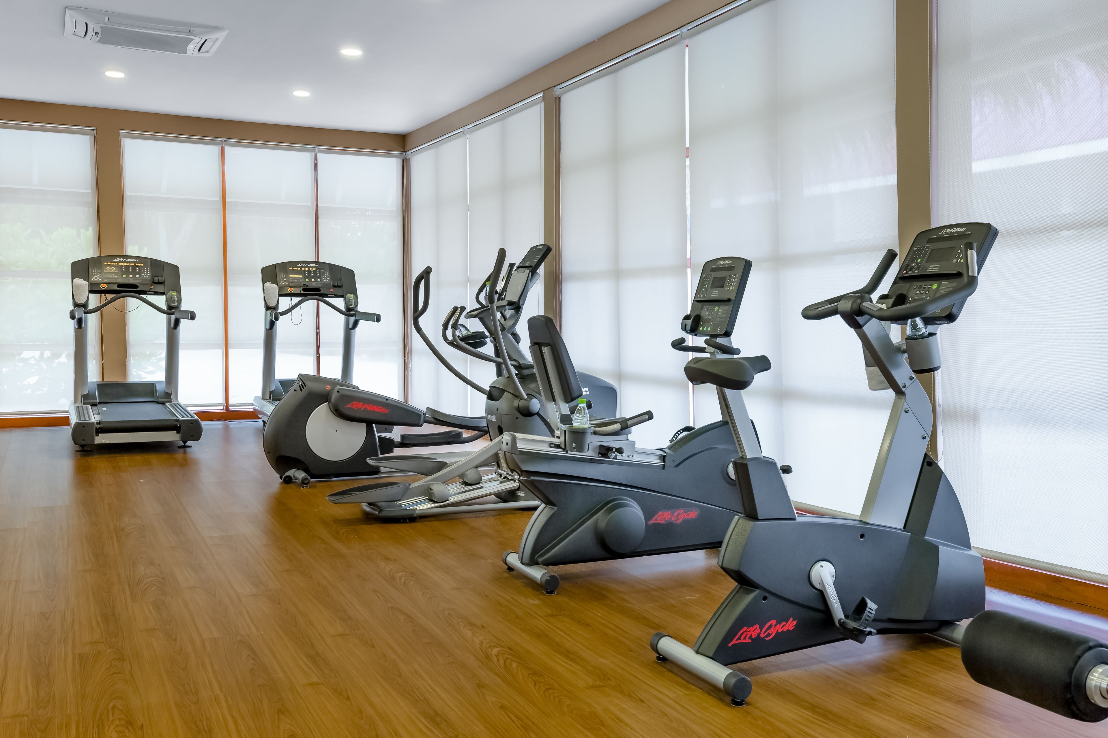 Een fitnessruimte met loopbanden, elliptische trainers en hometrainers.