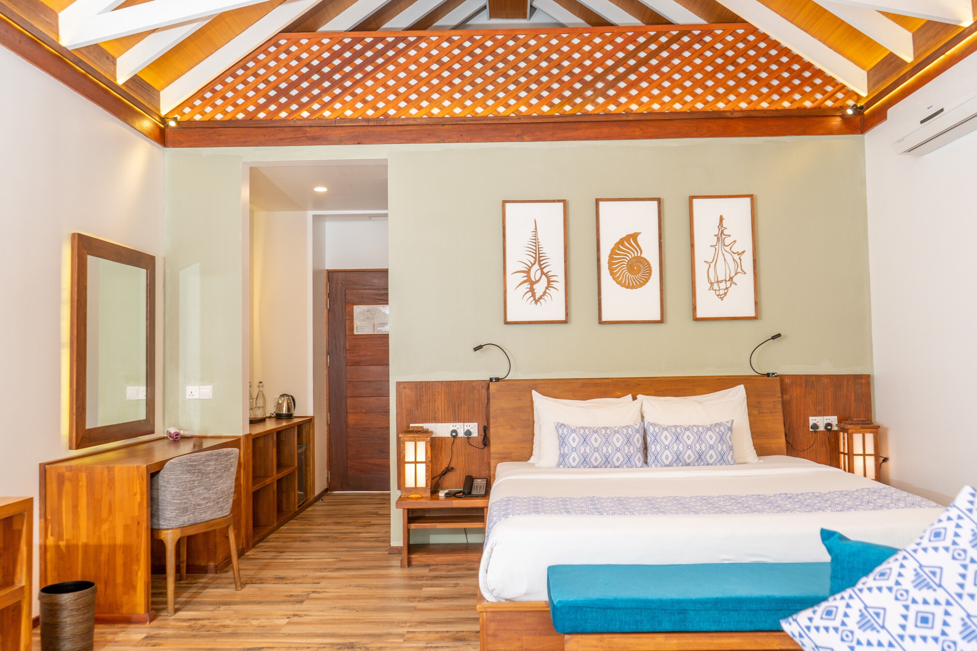 Un dormitorio con cabecera de madera, una cama grande con ropa de cama estampada, un escritorio con silla y una obra de arte colgada en la pared.