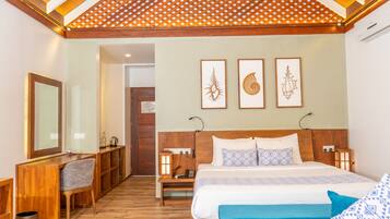 Un dormitorio con cabecera de madera, una cama grande con ropa de cama estampada, un escritorio con silla y una obra de arte colgada en la pared.