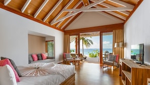 Une chambre spacieuse avec un grand lit, un plafond en bois et une vue sur l’océan.