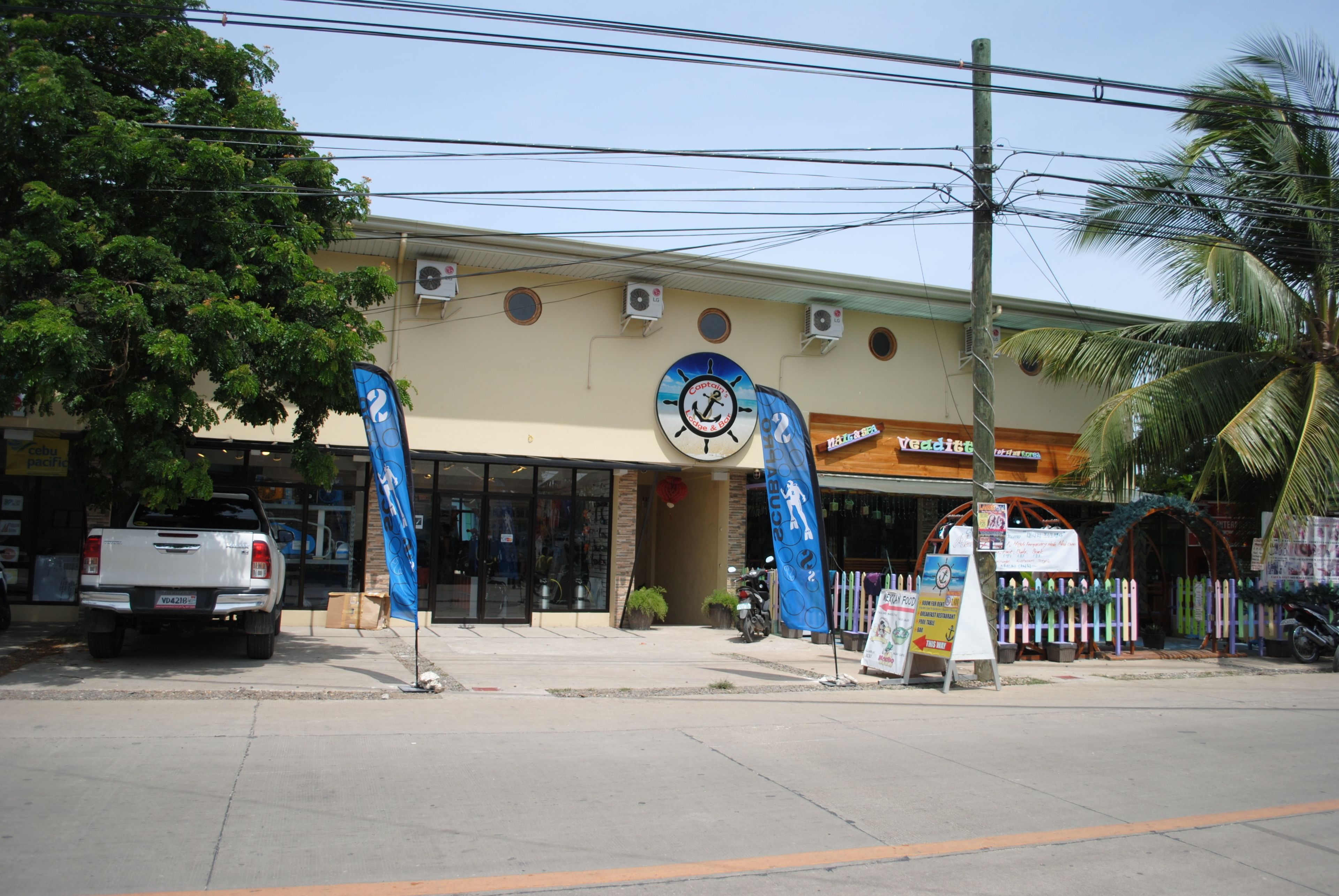 A building with a clock, palm trees, and a signboard.