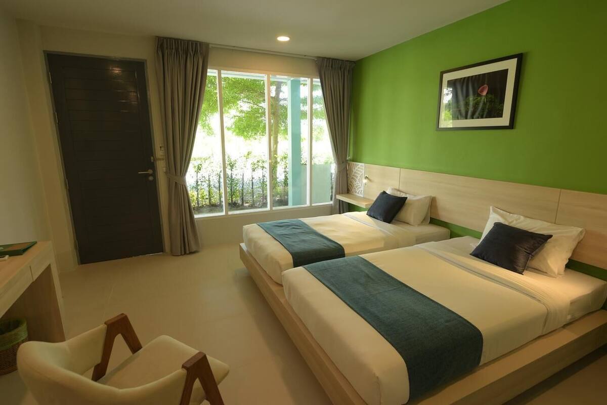 A hotel room with two beds, a desk, and a chair.