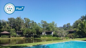 A swimming pool with a clear blue water surface, surrounded by lush greenery and trees. - The Touch Green Naiyang Hotel & Fitness (Sa Khu)
