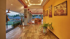 A spacious hallway with a wooden floor, a ceiling fan, and a view of a pool and buildings outside. - Seerock The King's Domain (Avudangawa)