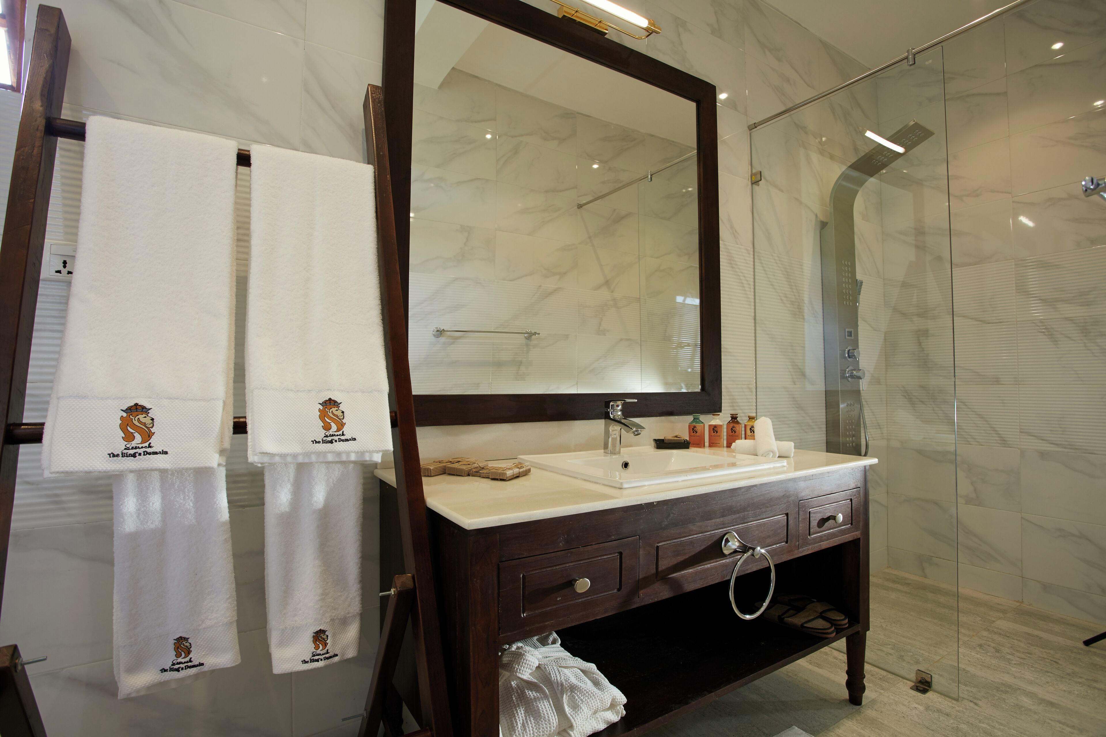 A bathroom with a marble sink, a large mirror, and two towels hanging on a rack.