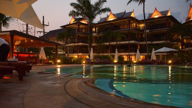 A resort with a swimming pool, multiple balconies, palm trees, and outdoor seating areas. - Kalim Residence Unit - 215 (Patong)