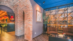 A bar area with a brick column, seating, and a wine display. - Kisi Boutique Hotel (Tbilisi)