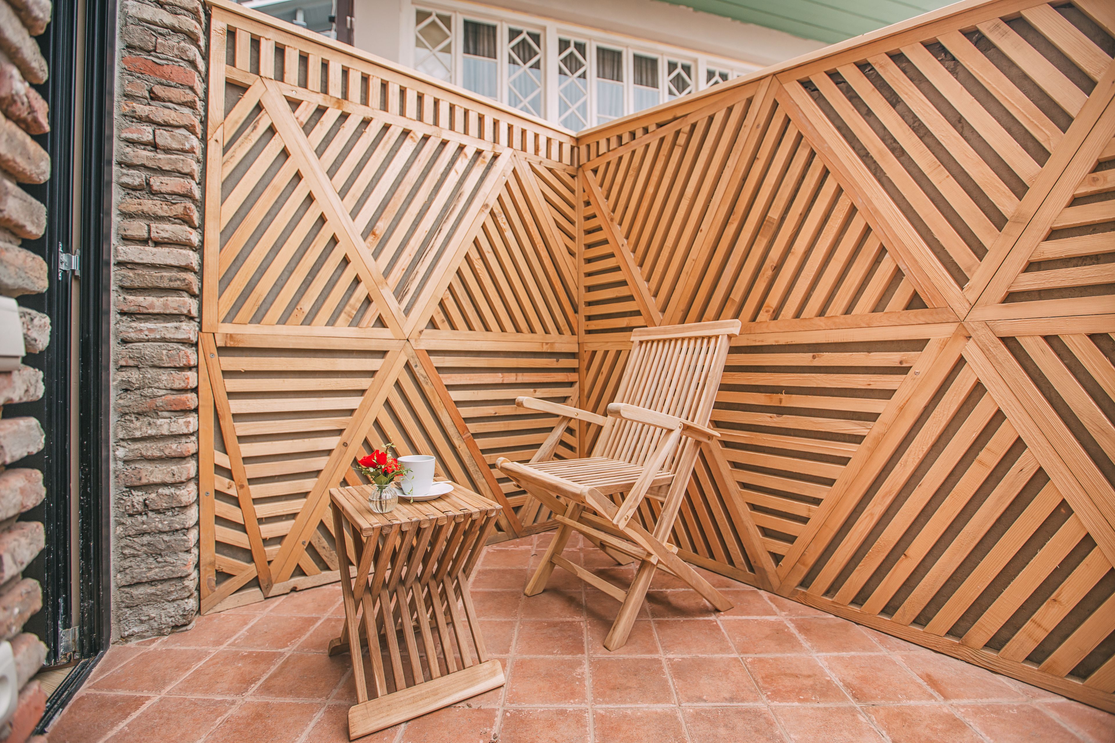 A wooden partitioned patio area with a table and two chairs.