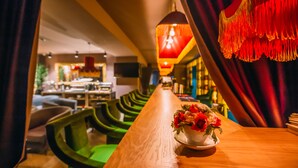 A bar area with a wooden counter, green upholstered chairs, and a decorative hanging light fixture. - Kisi Boutique Hotel (Tbilisi)