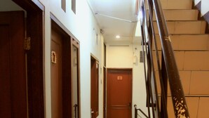 A hallway with wooden doors, a staircase with a metal railing, and a tiled floor. - Unique Guesthouse (Bandung)