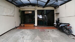 A covered entrance with a sign reading "Unique" and a motorcycle parked inside. - Unique Guesthouse (Bandung)
