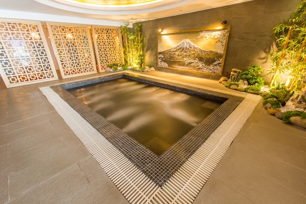 Un área de spa con un jacuzzi, paneles decorativos y una pintura del Monte Fuji.