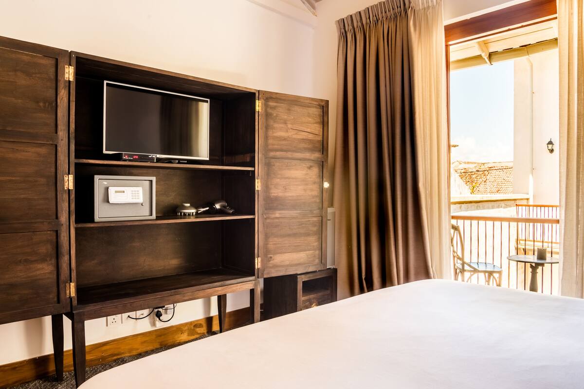 A hotel room with a bed, a TV, a safe, and a balcony with a view.