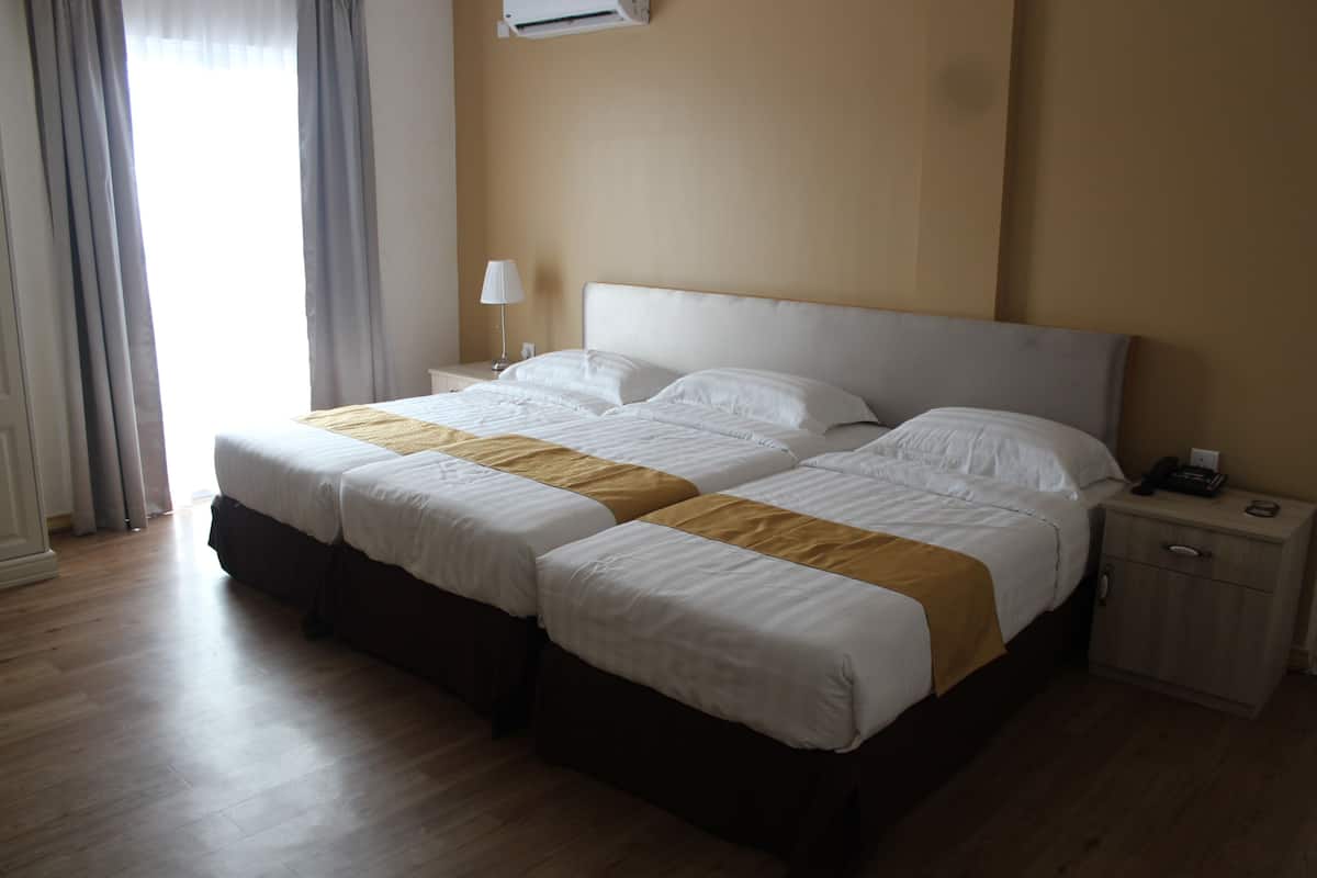 A hotel room with a double bed, a bedside table with a lamp, and a wall-mounted air conditioner.