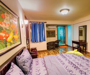 Une chambre d’hôtel avec un lit, une chaise, un bureau, un tableau et un rideau.