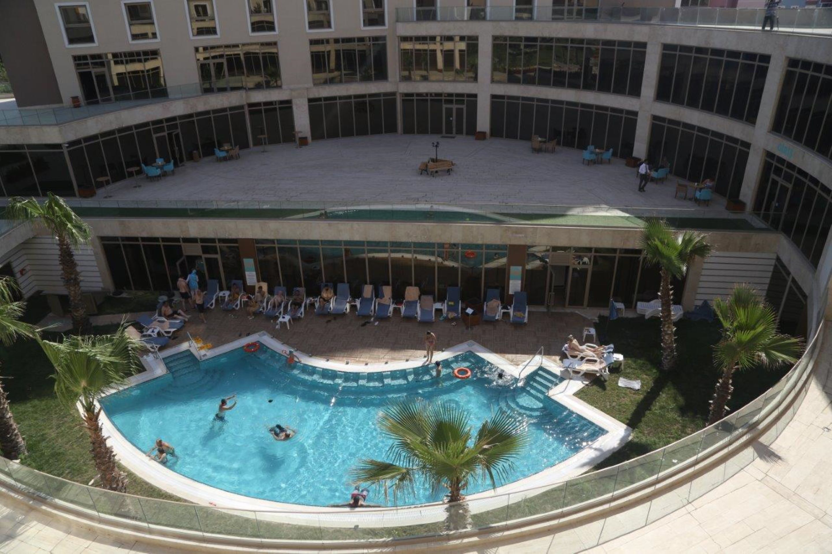A multi-level pool area with lounge chairs and palm trees.