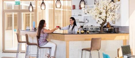 Een moderne hotellobby met een receptiebalie, een bar en zitplaatsen voor gasten.