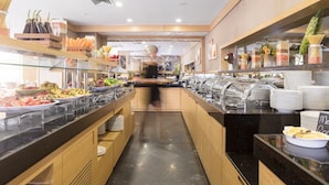 Uma área de buffet com diversas opções de comida, incluindo massas, saladas e frutas.