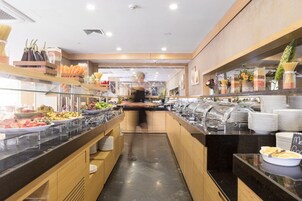 Zona de bufé con diversas opciones de comida, como pasta, ensaladas y frutas.