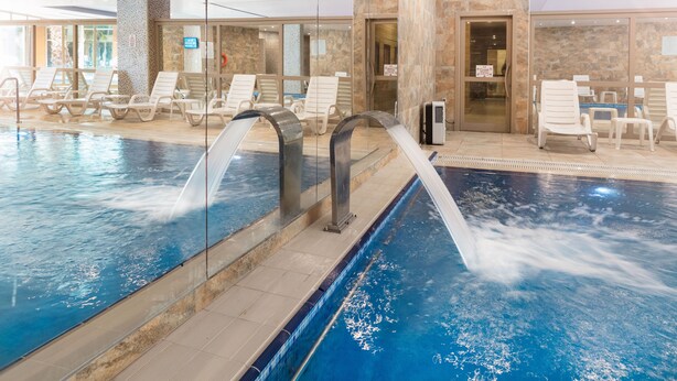 Piscina interna com espreguiçadeiras e área de recepção.
