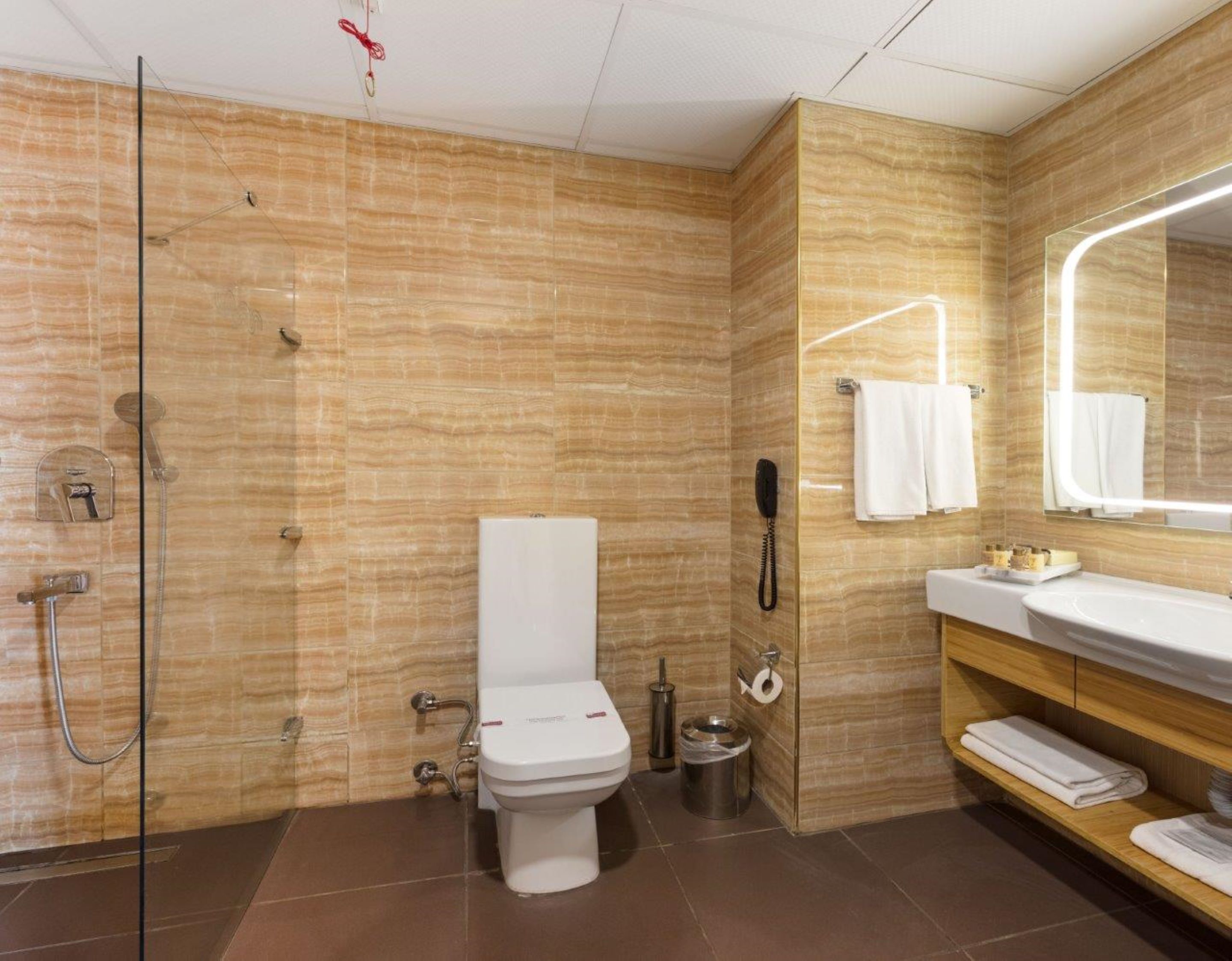 A modern bathroom with a glass shower enclosure, a toilet, a sink with a vanity, and a mirror.