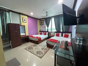 A hotel room with two beds, a TV, a desk, and a wardrobe.