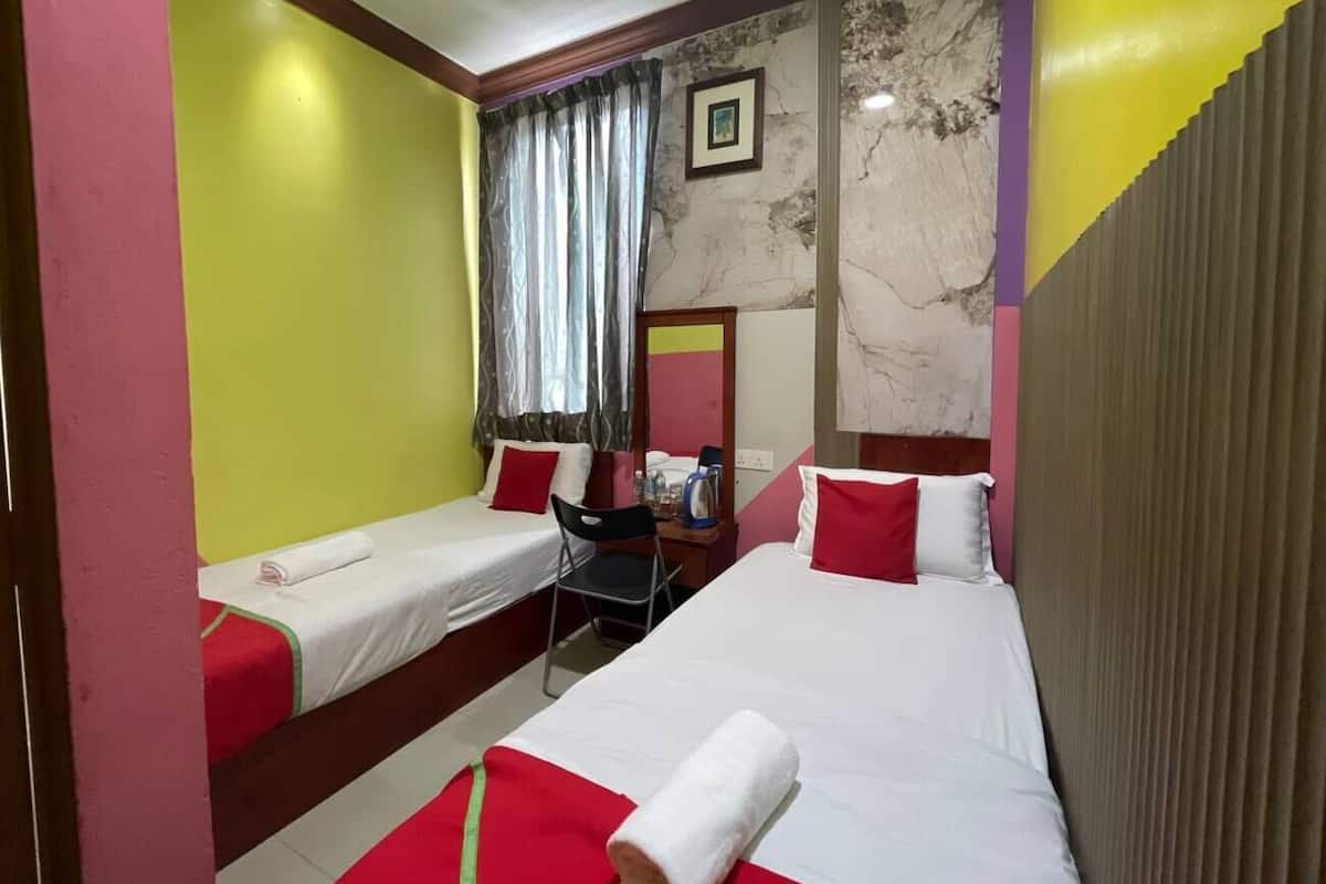 Une chambre d’hôtel avec deux lits simples, un bureau et une chaise.