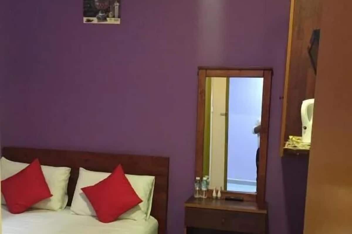 Une chambre d’hôtel avec un lit, un bureau, un miroir et une porte.