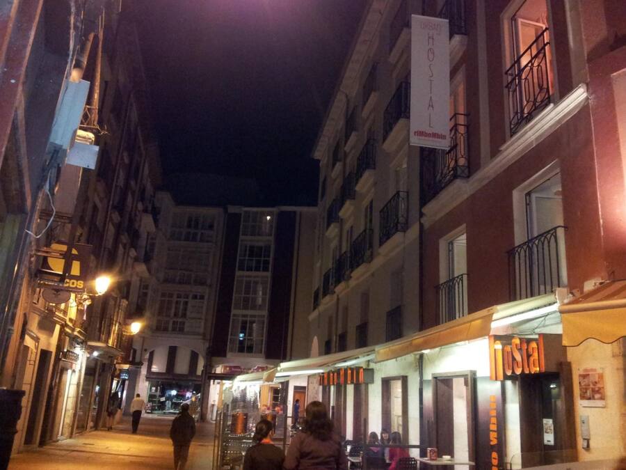 A narrow street lined with buildings, including a hostel with a sign.