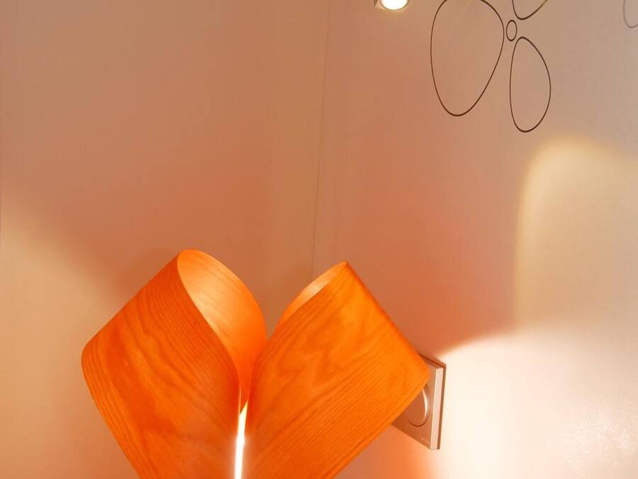 A modern lamp with a unique design on a bedside table in a hotel room.