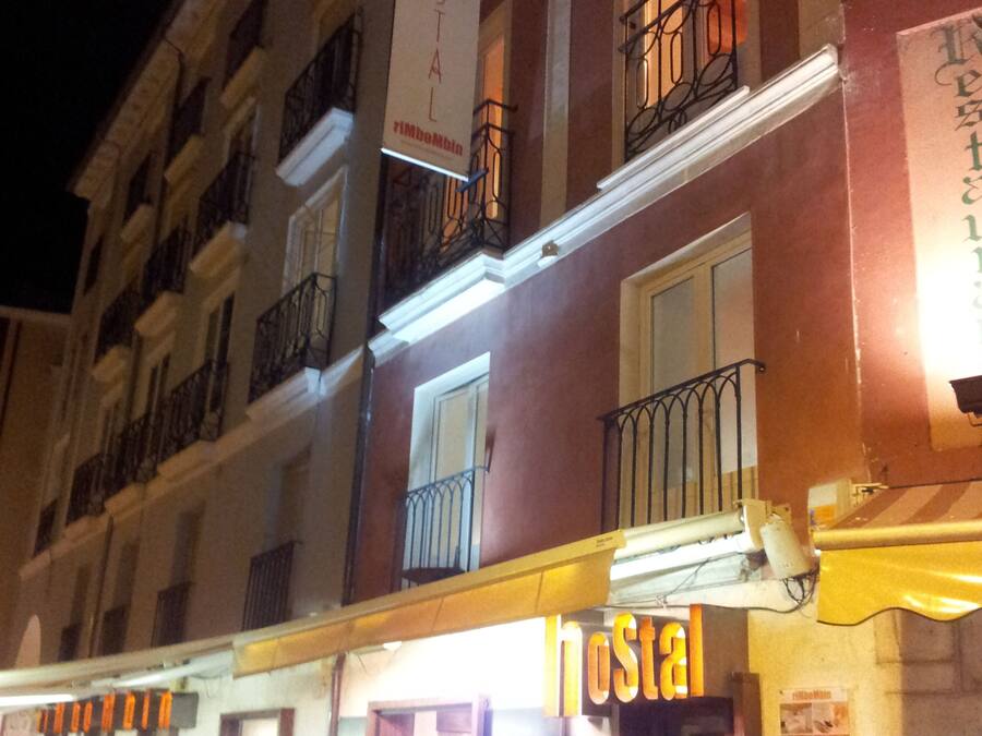 A building with a sign reading "Hostal" and a balcony with a railing.