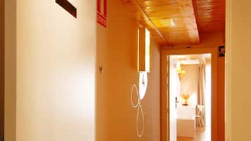 Un pasillo con techo de madera, una puerta con el número 42 y un cartel que indica una salida.