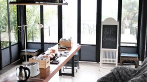 A room with a wooden table, a kettle, and a chalkboard sign reading "Self Service".