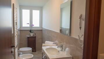A bathroom with a toilet, sink, and mirror.