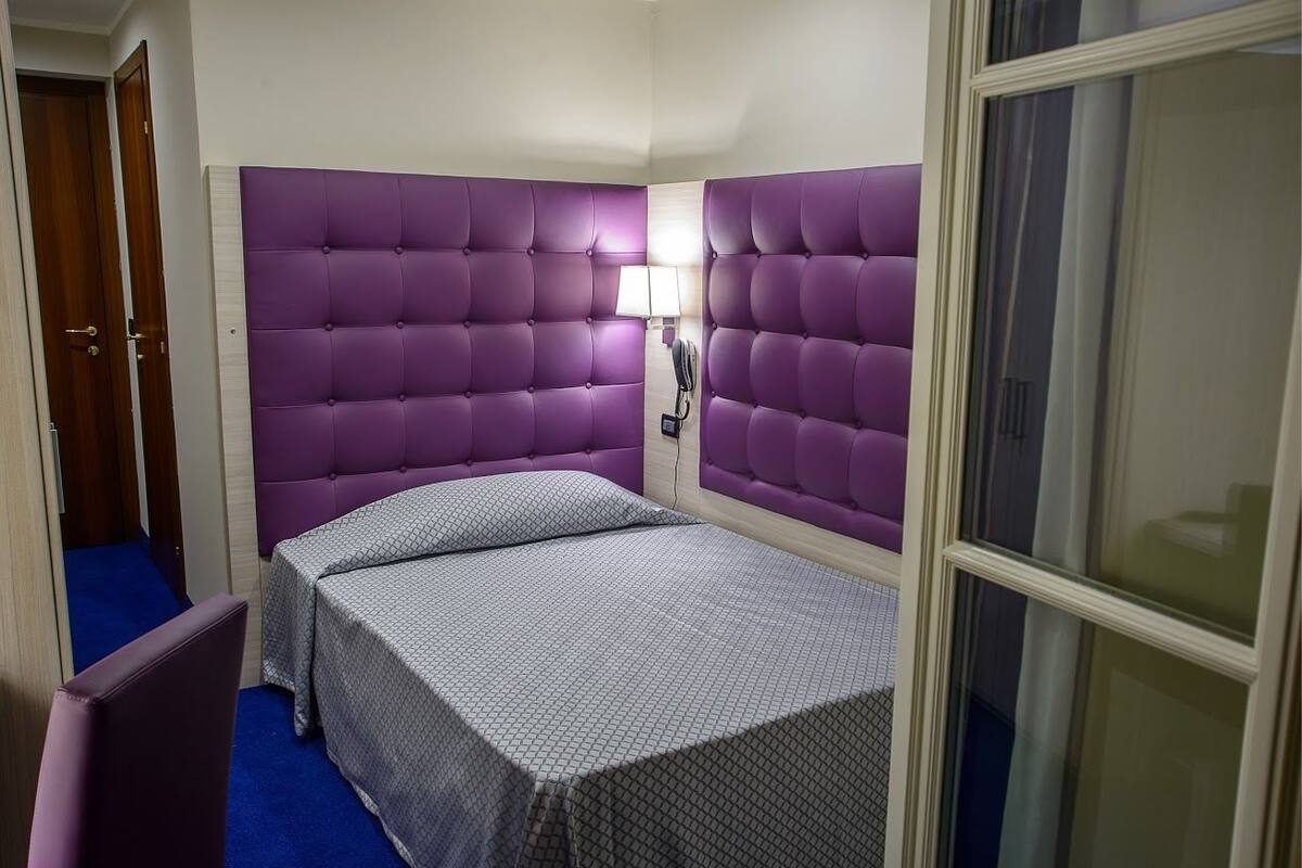 Une chambre d’hôtel avec un lit, une chaise et une fenêtre.