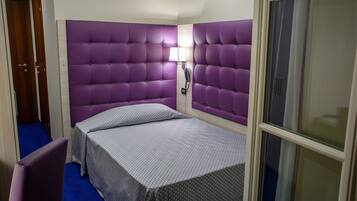 Una habitación de hotel con una cama, una silla y una ventana.