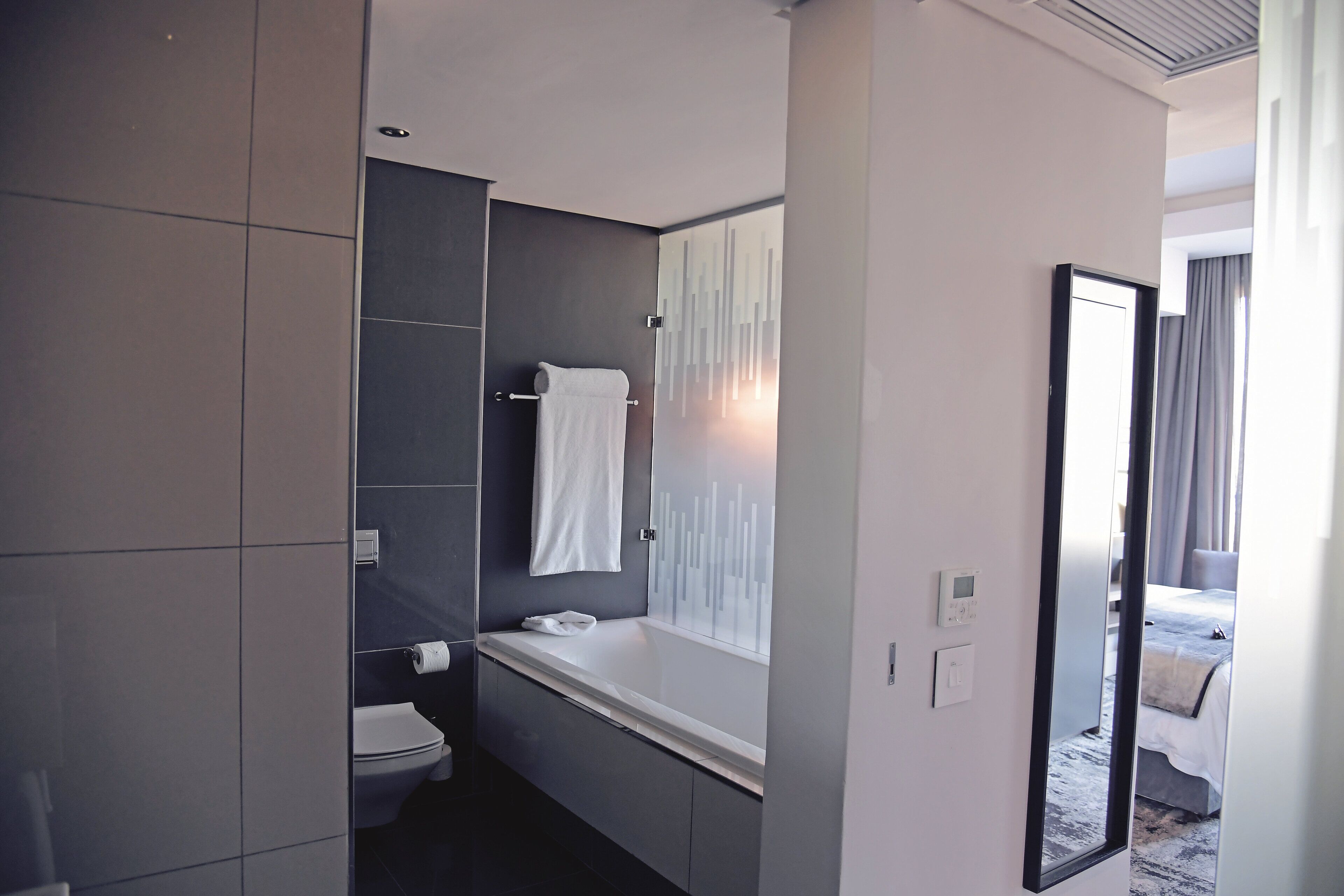 A modern bathroom with a bathtub, toilet, and a large mirror.