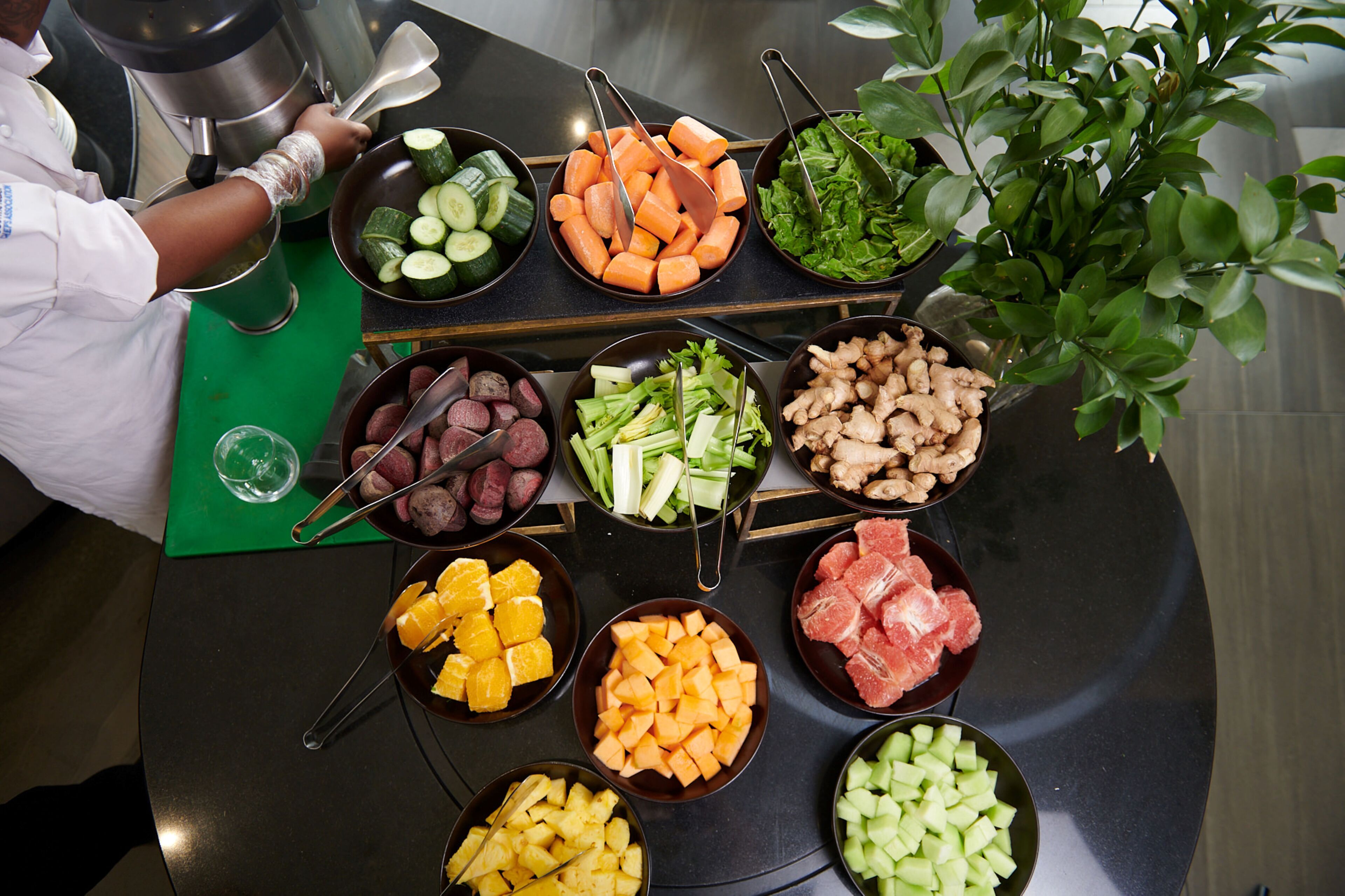 A buffet table with various food items including vegetables, fruits, and meats.