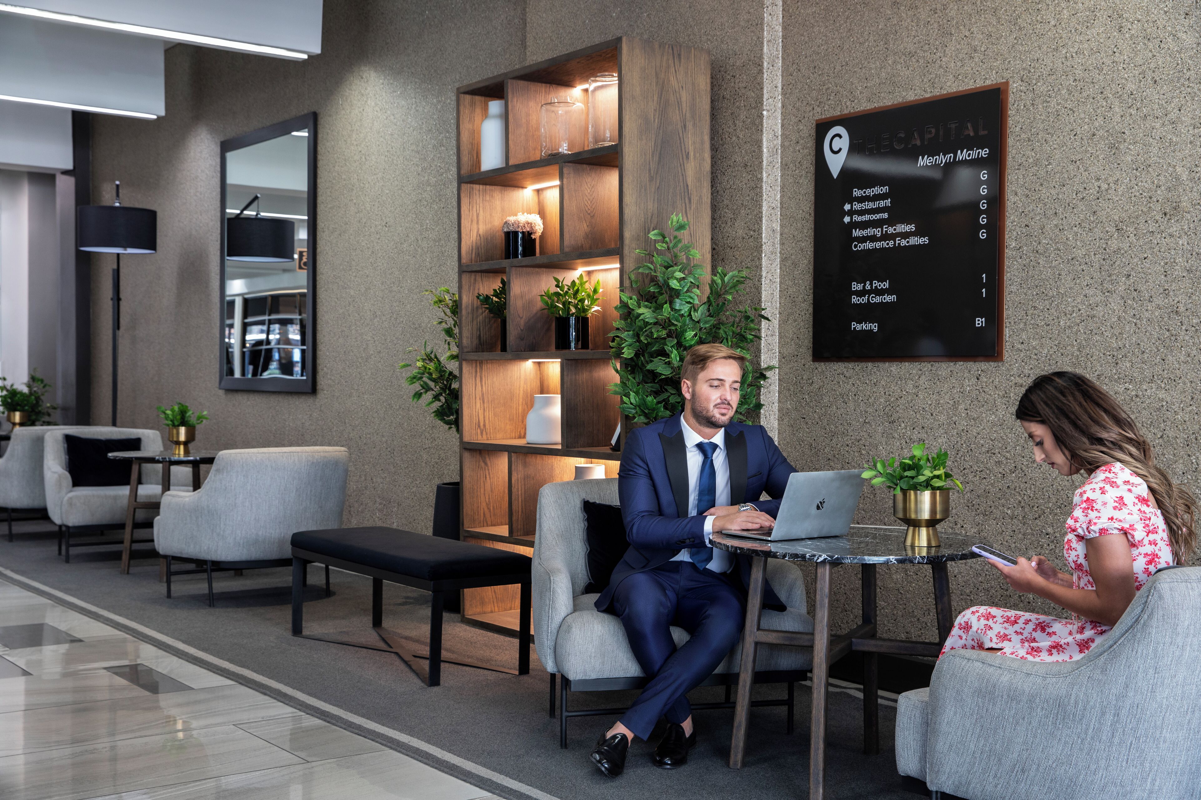 Un vestíbul modern amb taulell d'informació, zona de seients i un indicador que enumera serveis com a restaurant, lavabans i sales de conferències.
