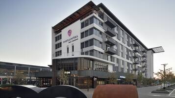 A modern hotel with multiple floors, balconies, and a prominent logo.